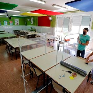 Dos docentes colocan los separadores en el comedor de un colegio Dos docentes colocan los separadores en el comedor de un colegio