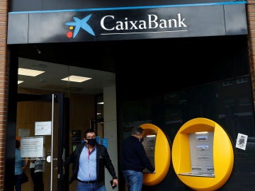 Varias personas operan en una sucursal de Caixabank Varias personas operan en una sucursal de Caixabank